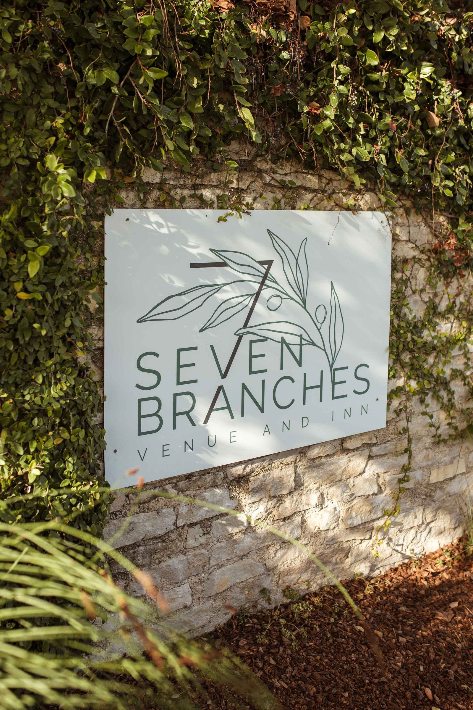 seven branches sign on a nice rock wall covered by green vegetation