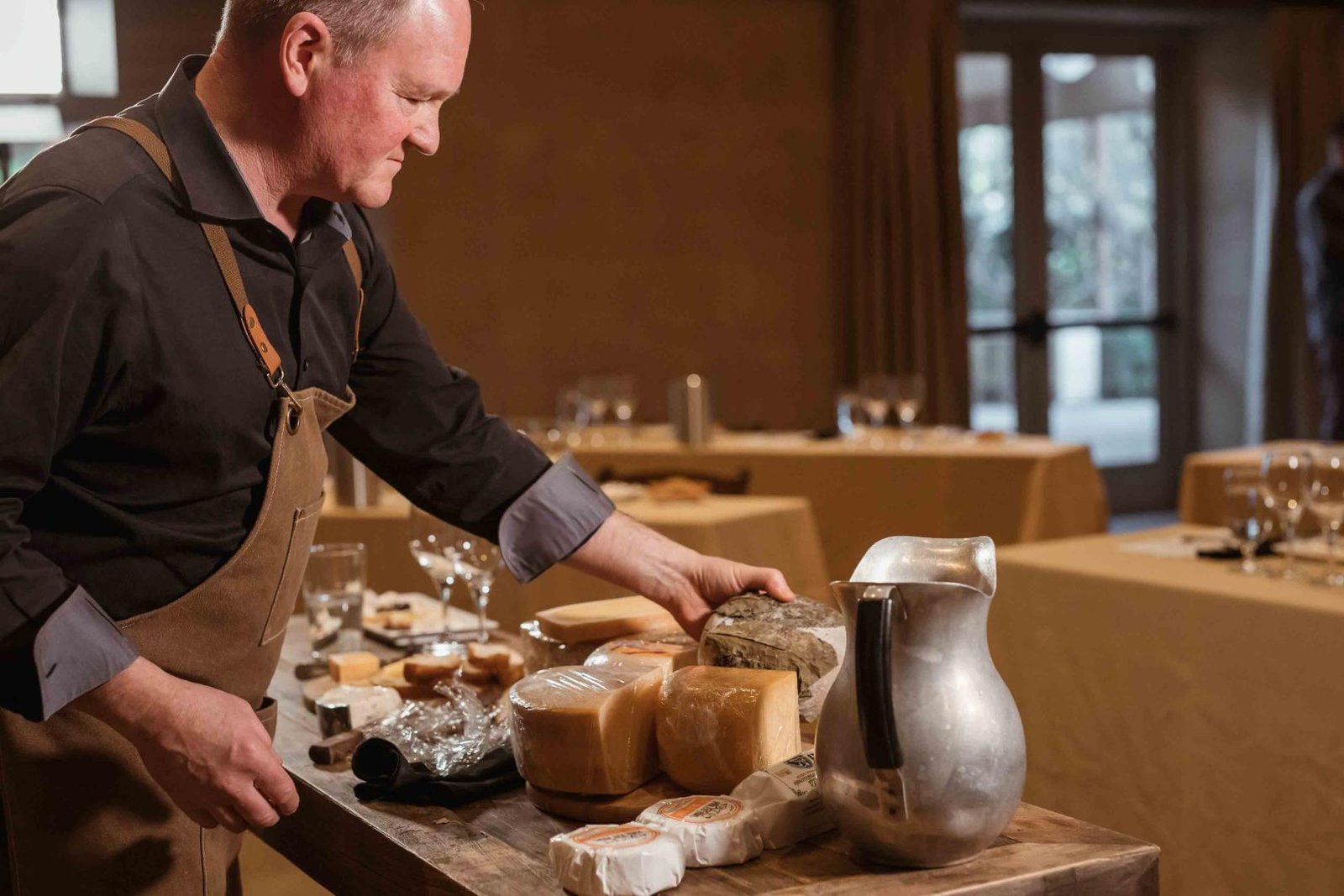 Cheesemonger Looking Through An Array Of Cheeses